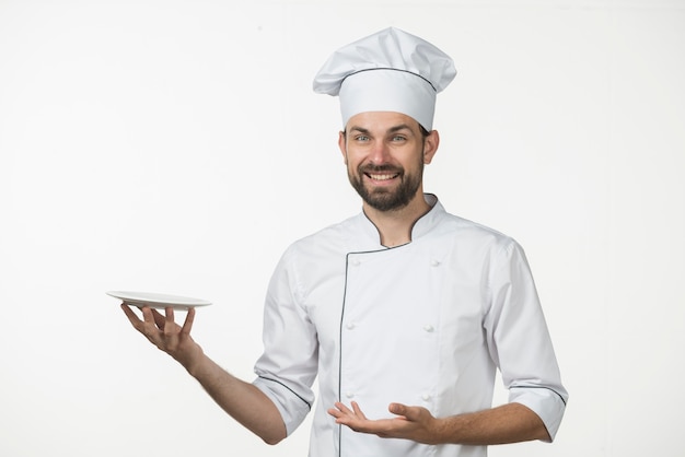 Foto cuoco unico maschio sorridente che presenta il suo piatto contro il contesto bianco