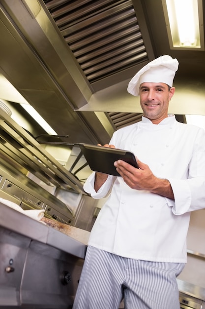 Smiling male cook using digital tablet in kitchen