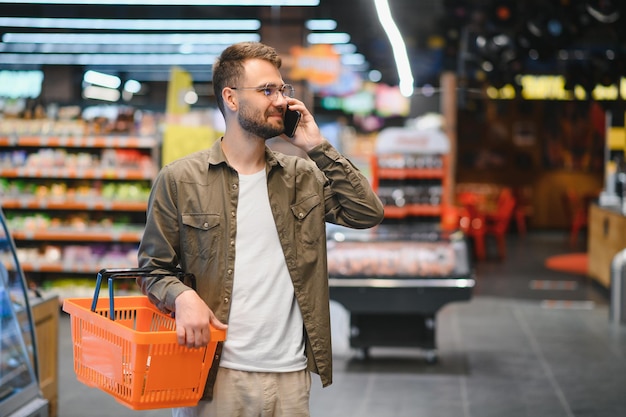 Улыбающийся мужчина делает покупки в продуктовом магазине