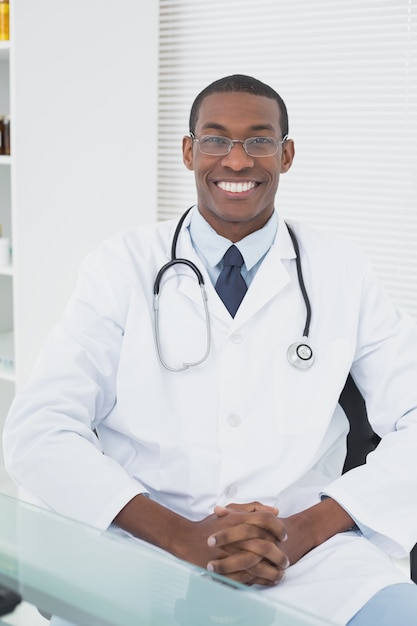 Photo smiling male doctor sitting at medical office