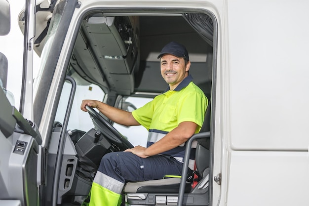 Smiling male driver sitting in truck and looking at camera