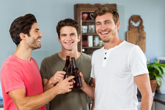 Smiling male friends toasting beer bottles