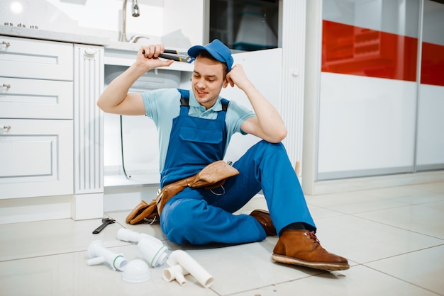 Smiling male plumber in uniform holds drain pipe