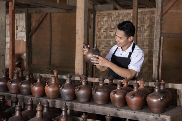 Smiling male potter holding his product in pottery workshop