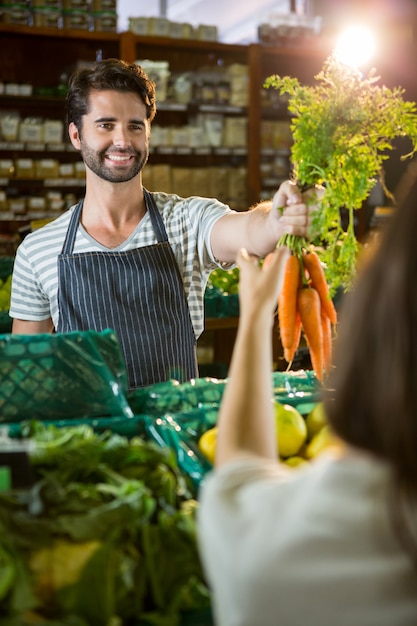 Smiling male staff assisting a woman with grocery shopping