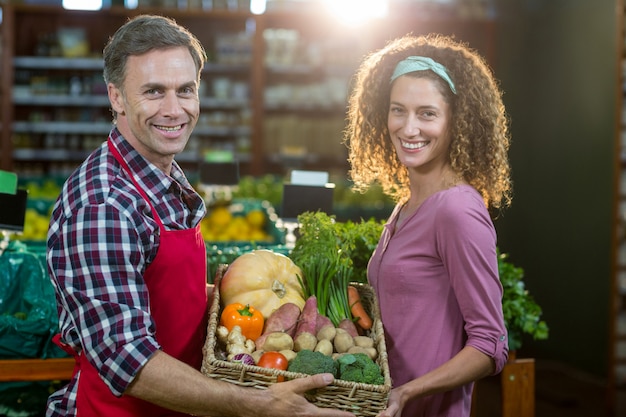 Smiling male staff assisting a woman with grocery shopping