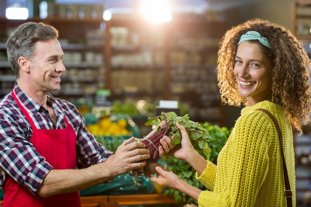 Smiling male staff assisting a woman with grocery shopping