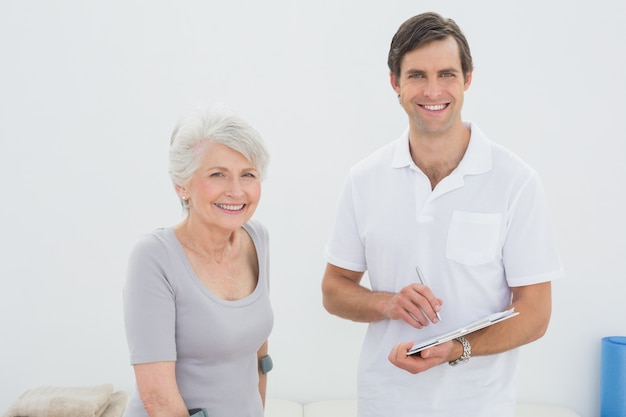 Terapista maschio sorridente e paziente senior disabile