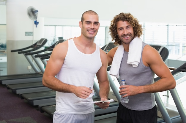 Smiling male trainer and fit man at gym