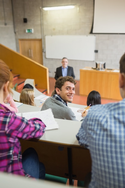 Улыбающийся мужчина со студентами и преподавателем в лекционном зале