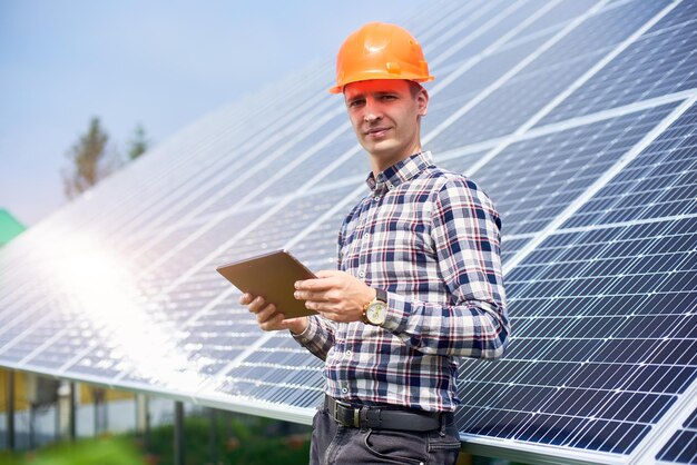 Smiling male with tablet in his hands near the solar station Green ecological power energy generation