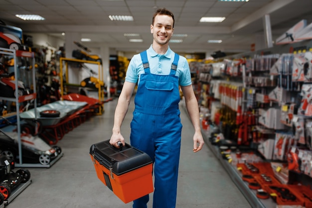 Smiling male worker in uniform buying toolbox in tool store