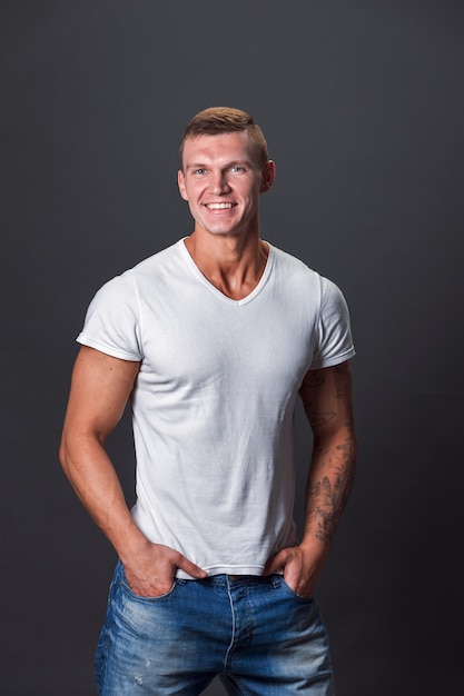 Uomo sorridente in maglietta in bianco, fondo grigio