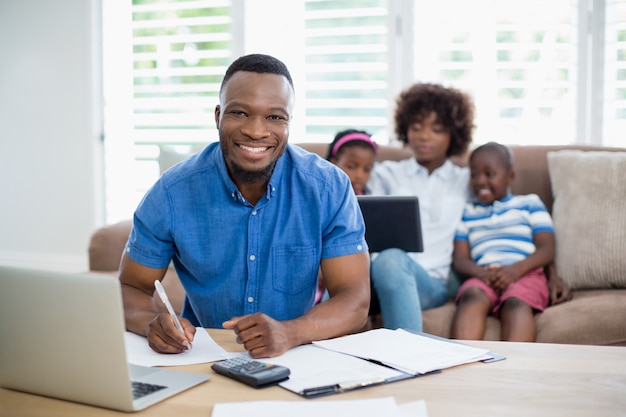 Smiling man calculating bills at home