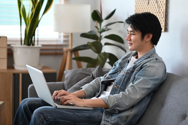 Smiling man in casual clothes working shopping online surfing internet with laptop at home