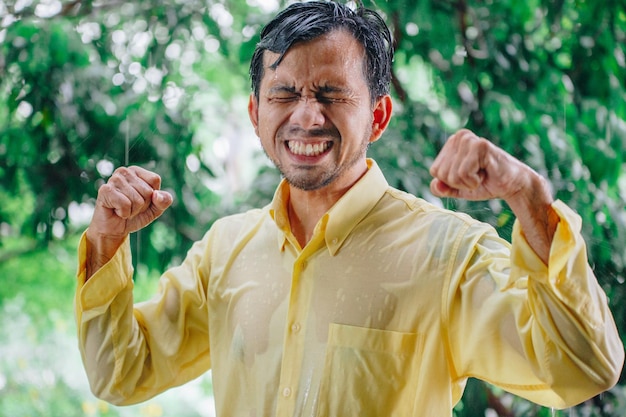 Smiling man celebrating success while standing against trees