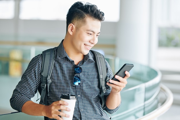 Uomo sorridente che controlla i messaggi di testo