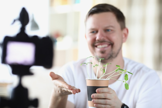 Smiling man demonstrates seedlings on video camera