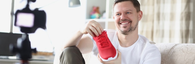 Smiling man demonstrates sneaker on video camera