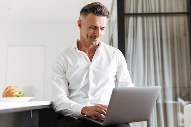 Smiling man dressed in formal clothes using laptop