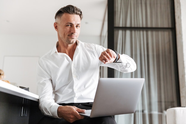 Smiling man dressed in formal clothes using laptop