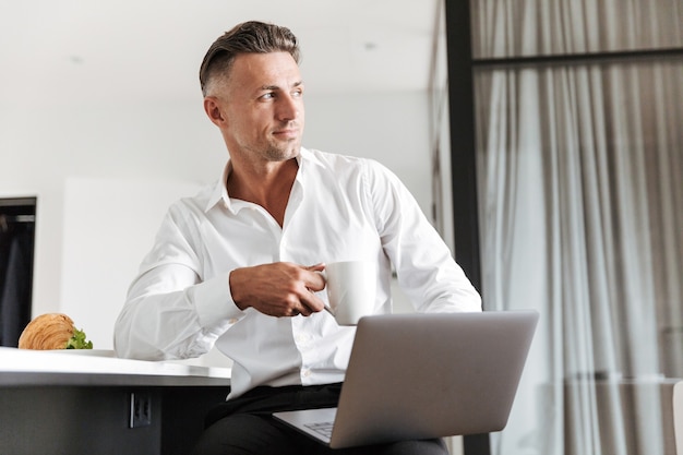 Smiling man dressed in formal clothes using laptop