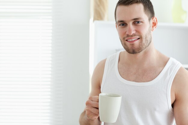 Smiling man drinking coffee in his kitchen