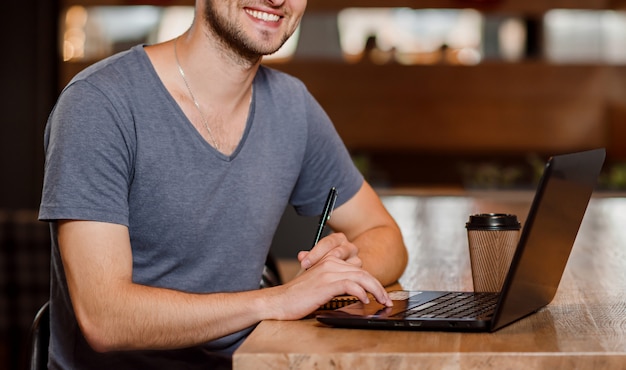 Smiling man drinking coffee and working in cafe.