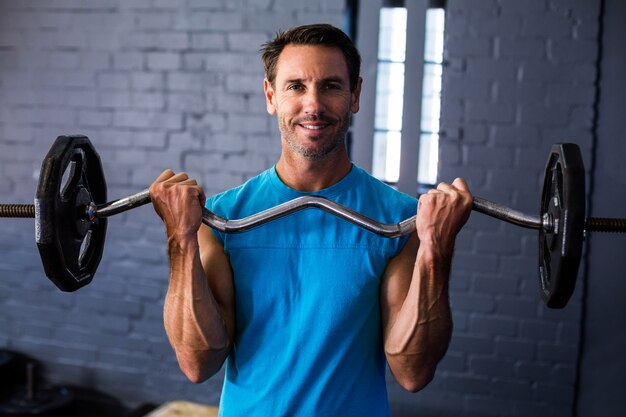 Smiling man exercising with barbell