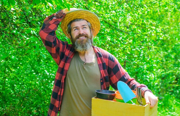 Smiling man in garden with gardening tools.