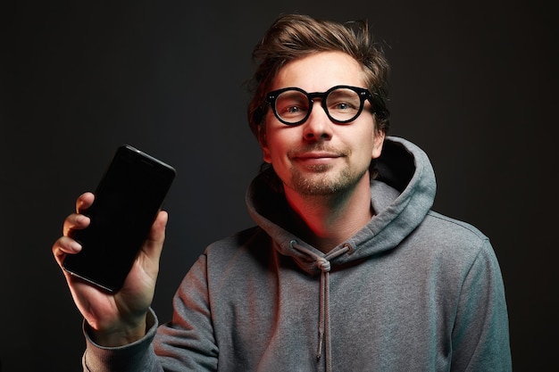 Smiling Man in glasses Happy guy holding and showing his smartphone