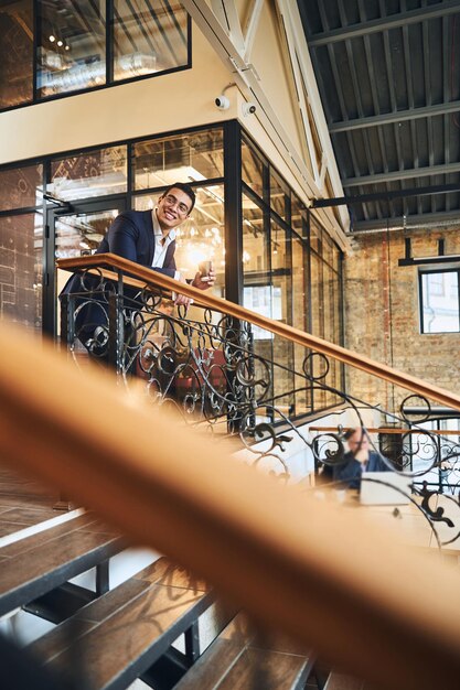 Smiling man in glasses leaning on the handrail