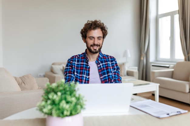안경을 쓴 웃고 있는 남자가 사무실 책상에 앉아 노트북 작업을 하는 동안 데이터를 보고 있다