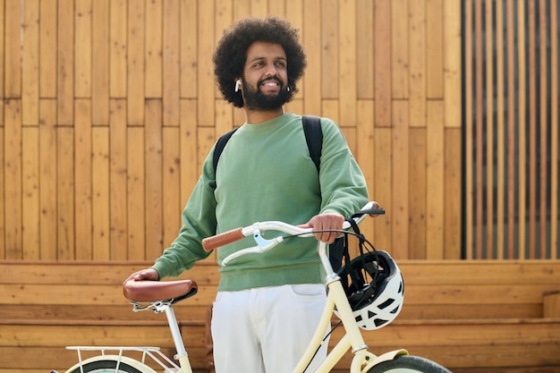 Smiling Man Handling Bicycle with Wooden Background