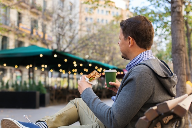 ベンチに座って昼食をとっている笑顔の男