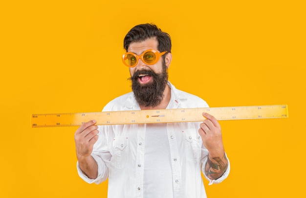 Smiling man hold geometry ruler on background photo of man hold geometry ruler man hold geometry ruler isolated on yellow man hold geometry ruler in studio