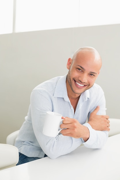 Улыбающийся человек с чашкой кофе у себя дома