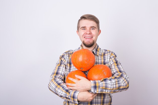 Uomo sorridente che tiene le zucche su sfondo bianco