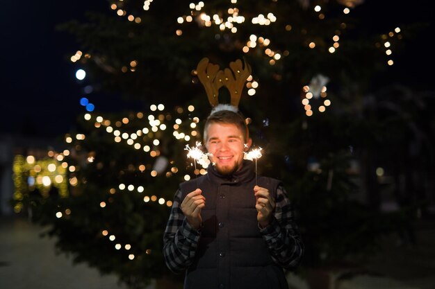 Photo smiling man holding sparkler at night