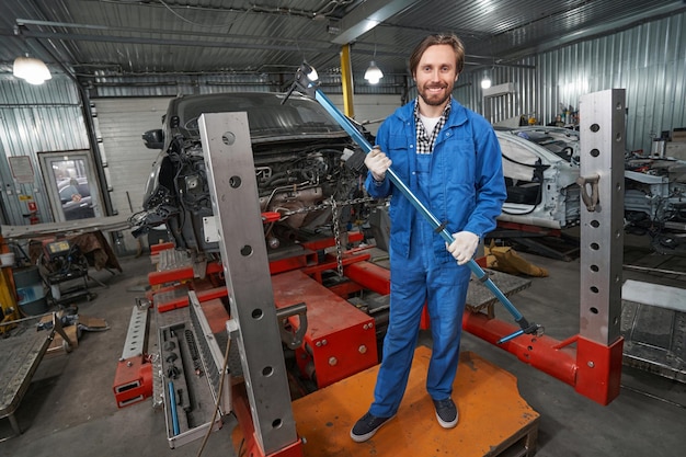 Photo smiling man holding special tool for auto repair