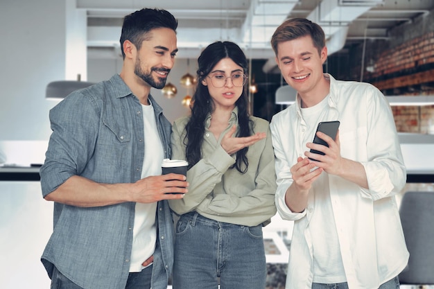 Smiling man holds smartphone shows colleagues in the modern office Startup management