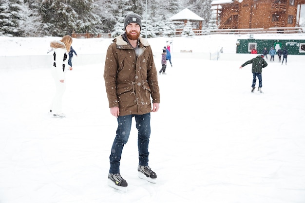 Улыбающийся человек на коньках на открытом воздухе со снегом