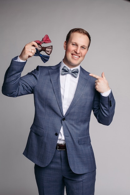 Photo smiling man insmart suit keeping bow ties in hand