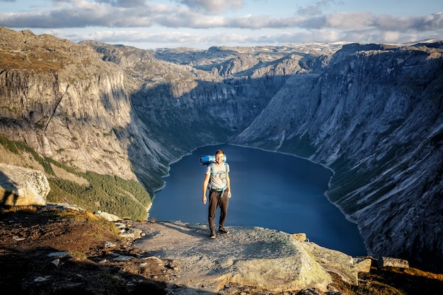 Smiling man is hiking the mountains with a backpack.