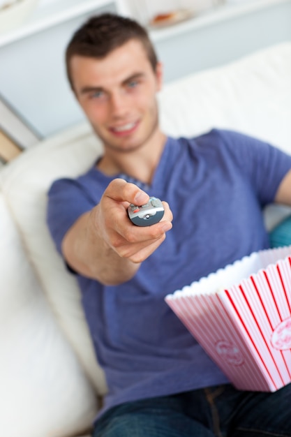 Foto l'uomo sorridente sta rilassando nel salone con popcorn