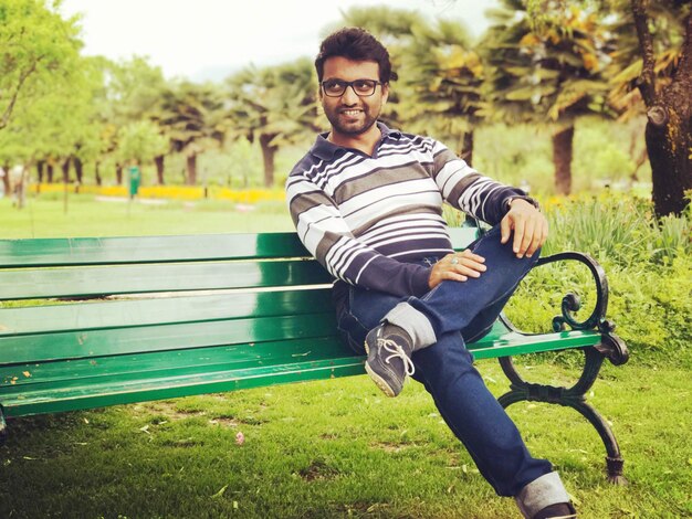 Photo smiling man looking away sitting on bench at park