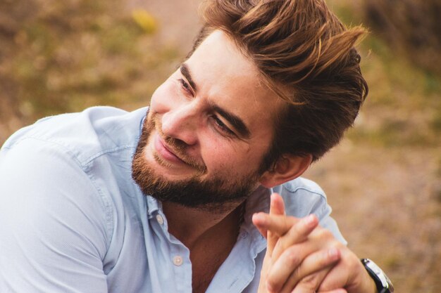 Foto uomo sorridente che guarda lontano seduto all'aperto