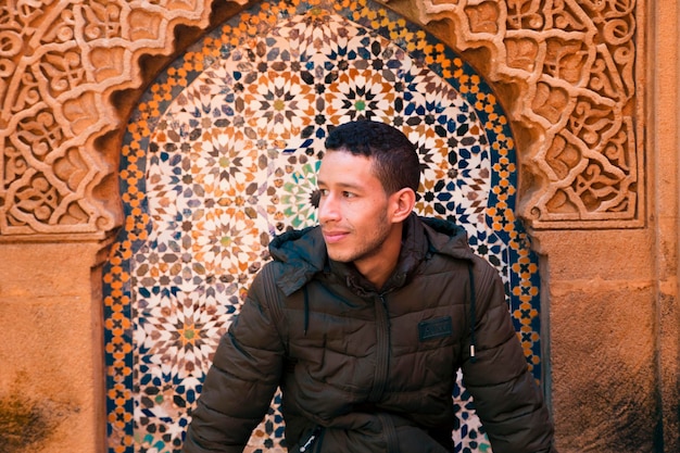 Foto uomo sorridente che guarda lontano mentre è seduto in un luogo storico