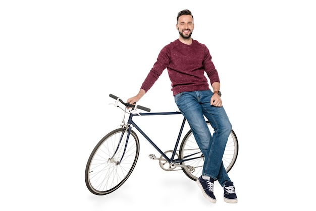 Smiling man looking at camera while leaning on bicycle isolated on white