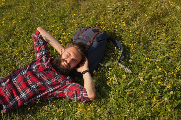 Photo smiling man lying on backpack